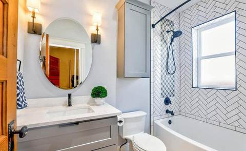 Bright, clean bathroom with a vanity, round mirror and tub