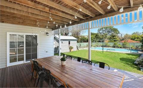 Covered patio with a long dining table and a view of a pool and yard