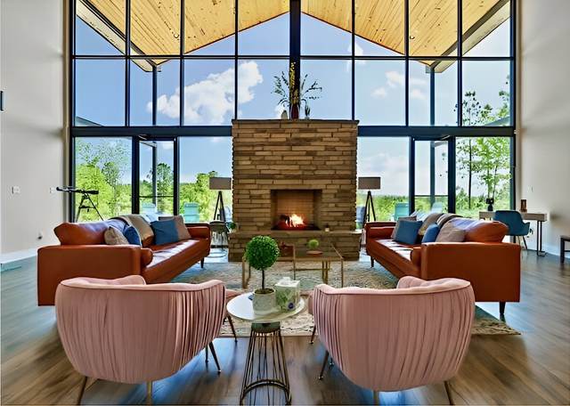 Vacation rental living room with floor-to-ceiling windows, a stone fireplace and pink armchairs
